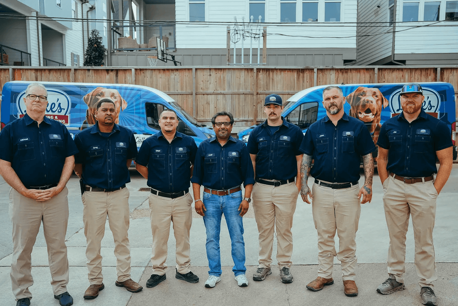 The Luke's Plumbing & Air Conditioning team standing in front of their branded service vans outside the Houston shop