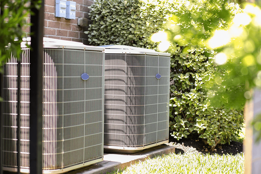 Two residential outdoor AC condenser units beside a Houston home