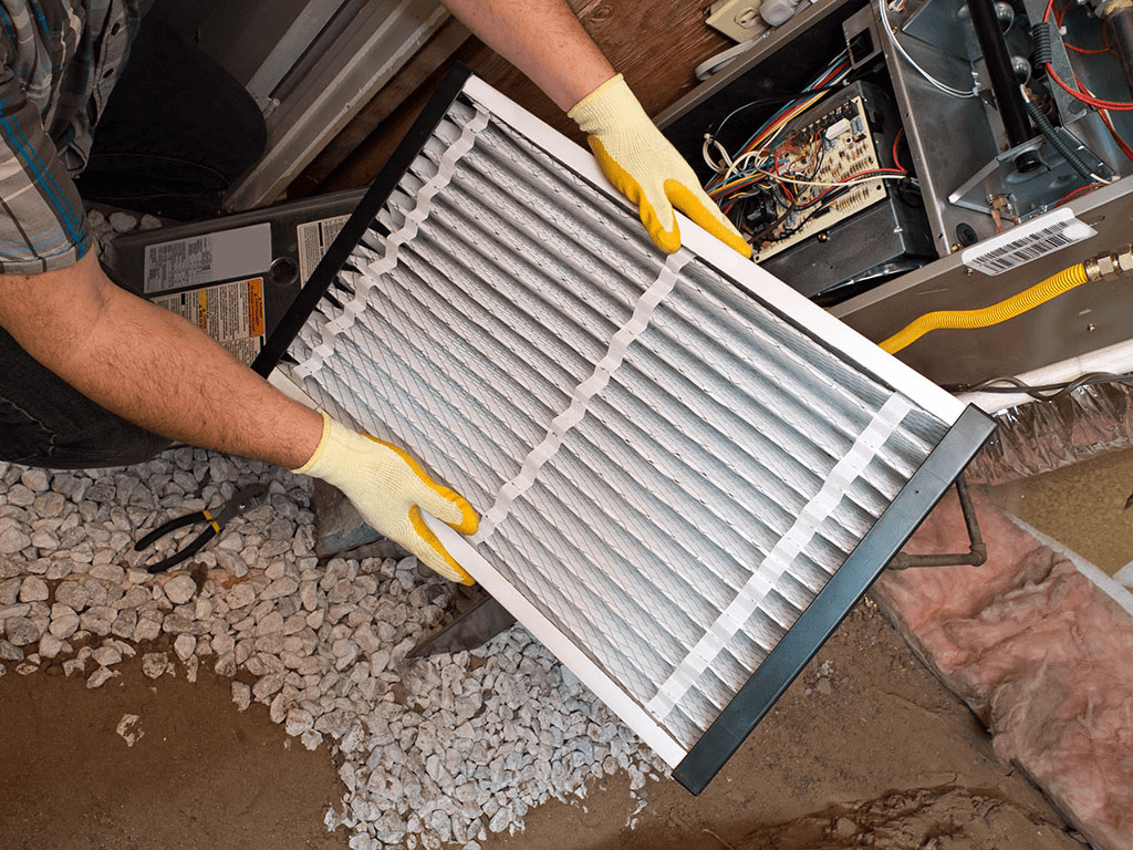Technician replacing a furnace filter during routine heating maintenance